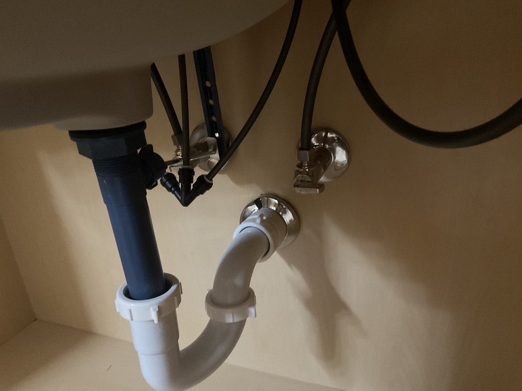 Under-sink plumbing with pipes and hoses