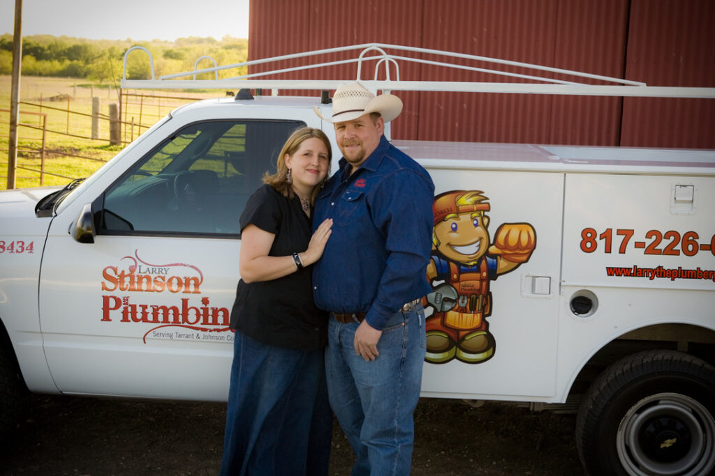 Couple standing by plumbing service truck