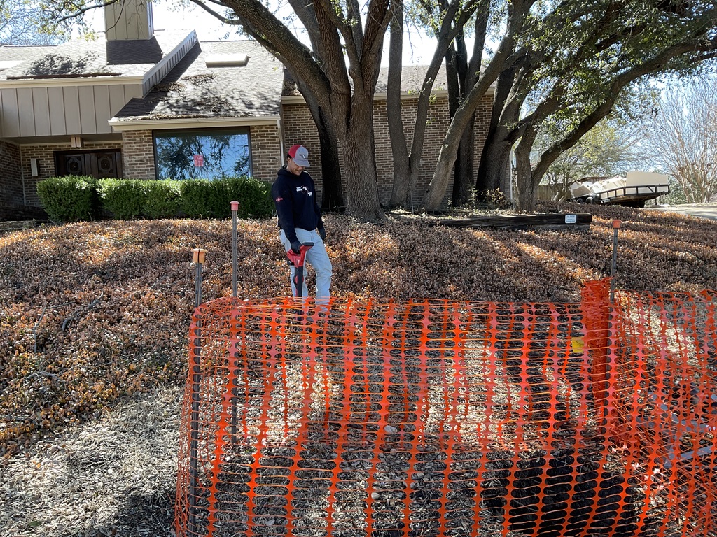 Worker near construction site with orange safety fence.