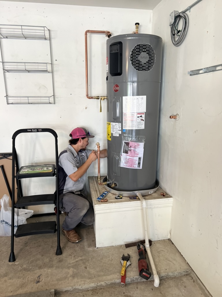 Technician installing a water heater in utility room.