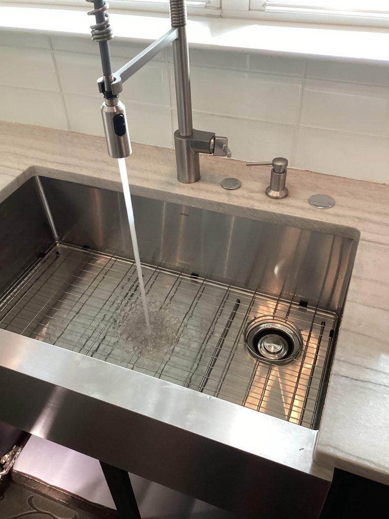 Stainless steel kitchen sink with running water faucet.